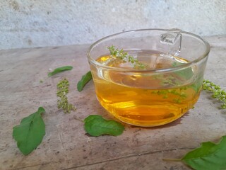 Tulsi tea is served in a cup with fresh leaves on the side of the selected focus.