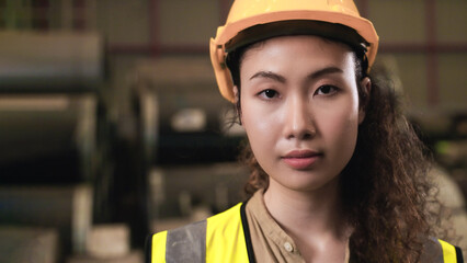 Portrait of happy professional Asian woman worker wearing yellow safety hard hat standing and...