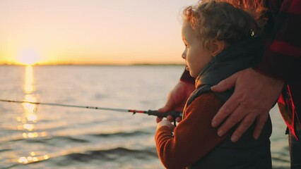 cute little boy is fishing by rod, father or grandpa is helping to child, happy family on river shore in sunset - Powered by Adobe