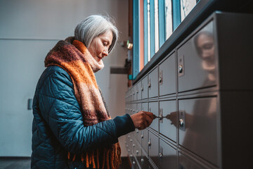 Senior woman opens the mailbox to check for new mails