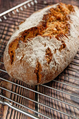 A loaf of crusty bread on rustic wooden table. On an oven rack.