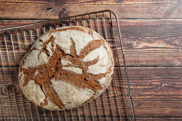 A loaf of crusty bread on rustic wooden table. On an oven rack.