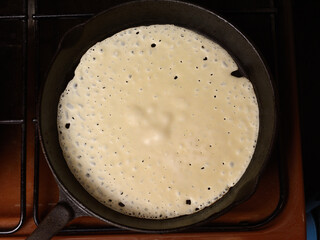 Pancakes baking in a hot frying pan, close-up view from above