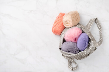 Fototapeta na wymiar pastel colored yarn wool in a fabric shopping bag on marble background