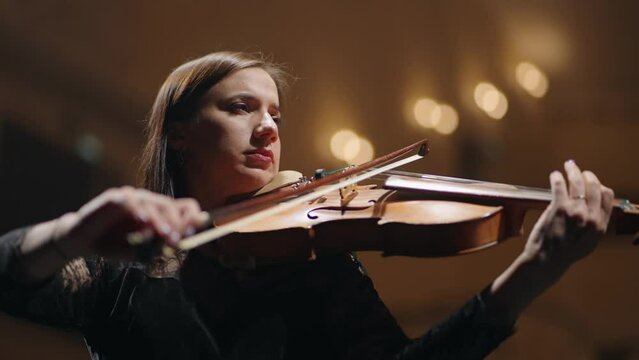 woman is playing viola in music hall, portrait of female musician on scene of music hall