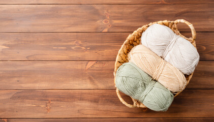 pastel colored yarn wool in a basket on wooden background