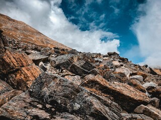 Rocky mountain slope against a cloudy blue sky in Sikkim, India