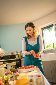 Young woman making a strawberry pie, in the kitchen. the sun enters through the window