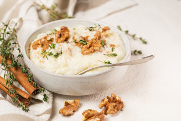 Focus selective photo of rice pudding finished with cinnamon powder, walnuts and thyme in white...