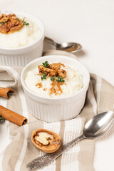 Two white forms whith rice pudding or porridgewhith cinnamon, walnuts and thyme  and teaspoons on...