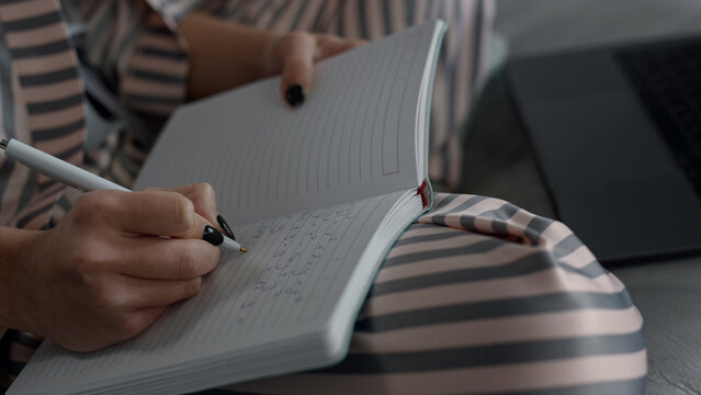 Student writing online lecture at home closeup. Smart girl studying remotely