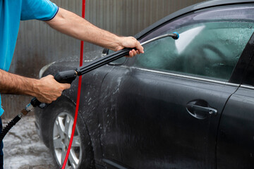 Car washing.  Mature man cleaning automobile with foam.Vehicle covered with foam shampoo chemical detergents during carwash self service