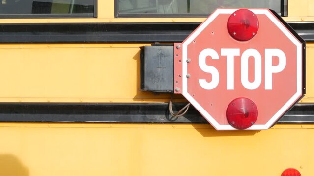 Red stop sign, yellow school bus in California, USA. Traffic warning on passenger schoolbus or shuttle in America. Public transportation safety on road. Caution or attention signage. Education concept