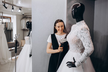 The dressmaker and the owner of her own room are ironing a wedding dress or a wedding dress with a...