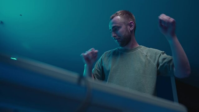 A music producer is dancing in a music studio. Electonic music.