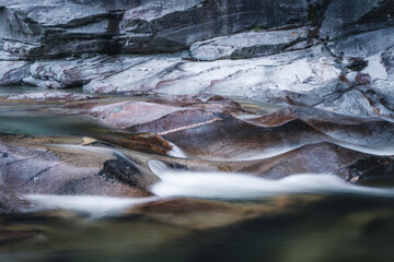 Atmosphärischer Naturhintergrund mit riesigen Steinen im Bergfluss. Große Felsen im mächtigen Wasserstrom, Nahaufnahme. Naturhintergrund mit Wald. Dunkel türkisblauer Fluss mit Steinen.