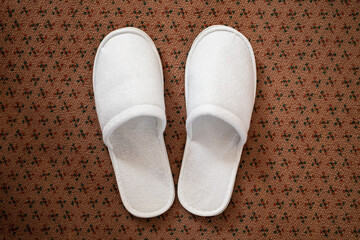 White slippers on the carpet in the hotel room. Top view. 