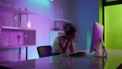 Competitive gamer playing esport computer game at neon lights home closeup.