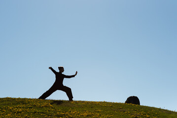 Asian woman practicing taijiquan at sunset, chinese martial arts, healthy lifestyle concept.