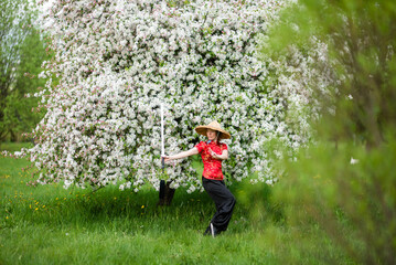 Asian woman with sword training with tai chi in the park, chinese martial arts, healthy lifestyle...