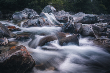 Atmosphärischer Naturhintergrund mit riesigen Steinen im Bergfluss. Große Felsen im mächtigen Wasserstrom, Nahaufnahme. Naturhintergrund mit Wald. Dunkel türkisblauer Fluss mit Steinen.