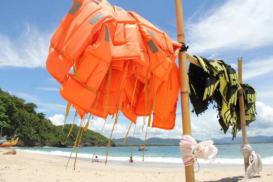 Bunch of orange and yellow life jackets on hanging on a bamboo pole at Papuma beach in Indonesia