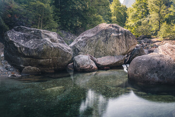 Atmosphärischer Naturhintergrund mit riesigen Steinen im Bergfluss. Große Felsen im mächtigen Wasserstrom, Nahaufnahme. Naturhintergrund mit Wald. Dunkel türkisblauer Fluss mit Steinen.