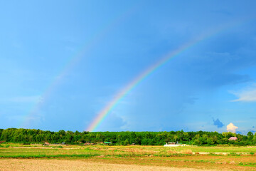 The countryside while it is raining and sunny, rainbow appear.