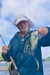 An angler with a crappie caught using a fly rod 
