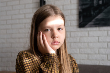 Little girl with toothache. A little girl has a swollen cheek due to a toothache. Little girl holds her cheek and her tooth hurts - obrazy, fototapety, plakaty