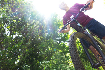 A teenager rides a bicycle on a road illuminated by the summer sun, cycling