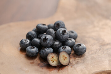 Fresh blueberries on wood board one berry is cut in halves