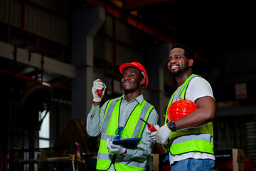 Two expert African American engineers are skilled in plant maintenance engineers. Discussing mechanical work on a black background of an industrial plant.Industrial engineer at manufacturing plant.