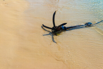 Small boat anchor on a shore of ocean