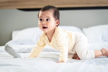 Fototapeta premium Asian baby girl with white skin and big eyes naughty age playing on the bed by the bedroom window