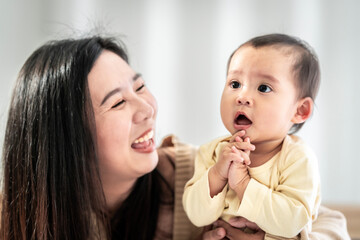 baby girl with asian mom smiling baby happily playing together in bed in the bedroom at home