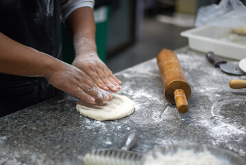 Hands of person rolling a dough for the cookies in flour.
