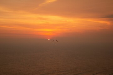 Bright golden sunset over the sea with one paraglider