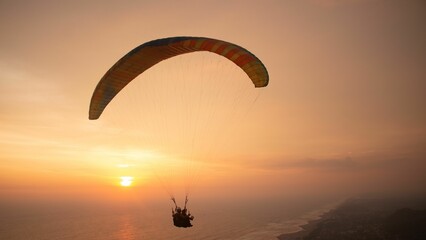 Tandem paragliding closeup over sea and beach while golden sunset