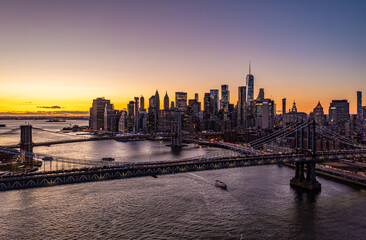 Large cable stayed bridges spanning East River. Skyline with downtown skyscrapers against romantic colourful sunset sky. Manhattan, New York City, USA