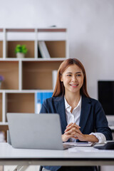 Asian Business woman using calculator and laptop for doing math finance on an office desk, tax, report, accounting, statistics, and analytical research concept