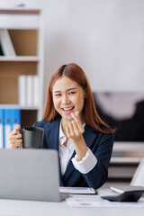 Asian Business woman using calculator and laptop for doing math finance on an office desk, tax, report, accounting, statistics, and analytical research concept