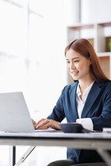 Asian Business woman using calculator and laptop for doing math finance on an office desk, tax, report, accounting, statistics, and analytical research concept