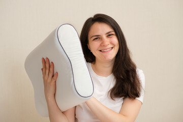 A woman holds an orthopedic pillow made of memory foam and smiles. Choosing the right pillow for...