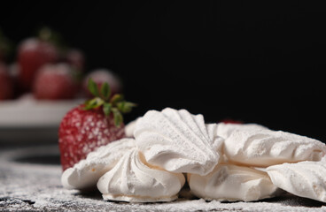 Fototapeta na wymiar Meringue and strawberries on a black background with space for text.