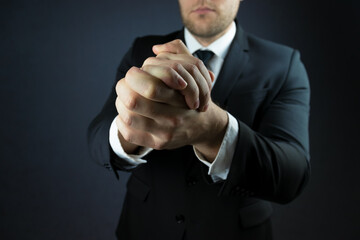 A businessman in a suit expresses a gesture of support with two hands folded together.