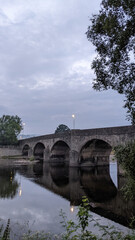 Old ancient traditional English stone bridge over calm countryside river