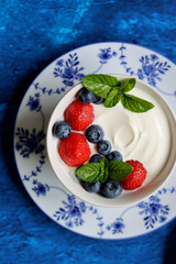 Homemade yogurt with fresh garden berries close up photo. Healthy summer breakfast on a table. Eating fresh concept. 