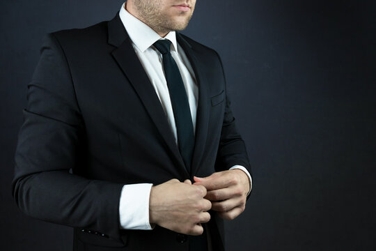 A businessman in a suit is buttoning his jacket.