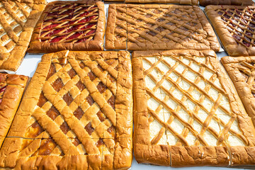 fresh baked big flat sweet open pies filled with various jams and cheese on table